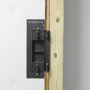 BreachPro MBI-HS hinge side breaching insert, MBI-DR door receiver, and MBI-M multi-method breaching insert installed in a residential training door mounted in the Modular Adjustable Breaching Facade for realistic tactical breaching training.