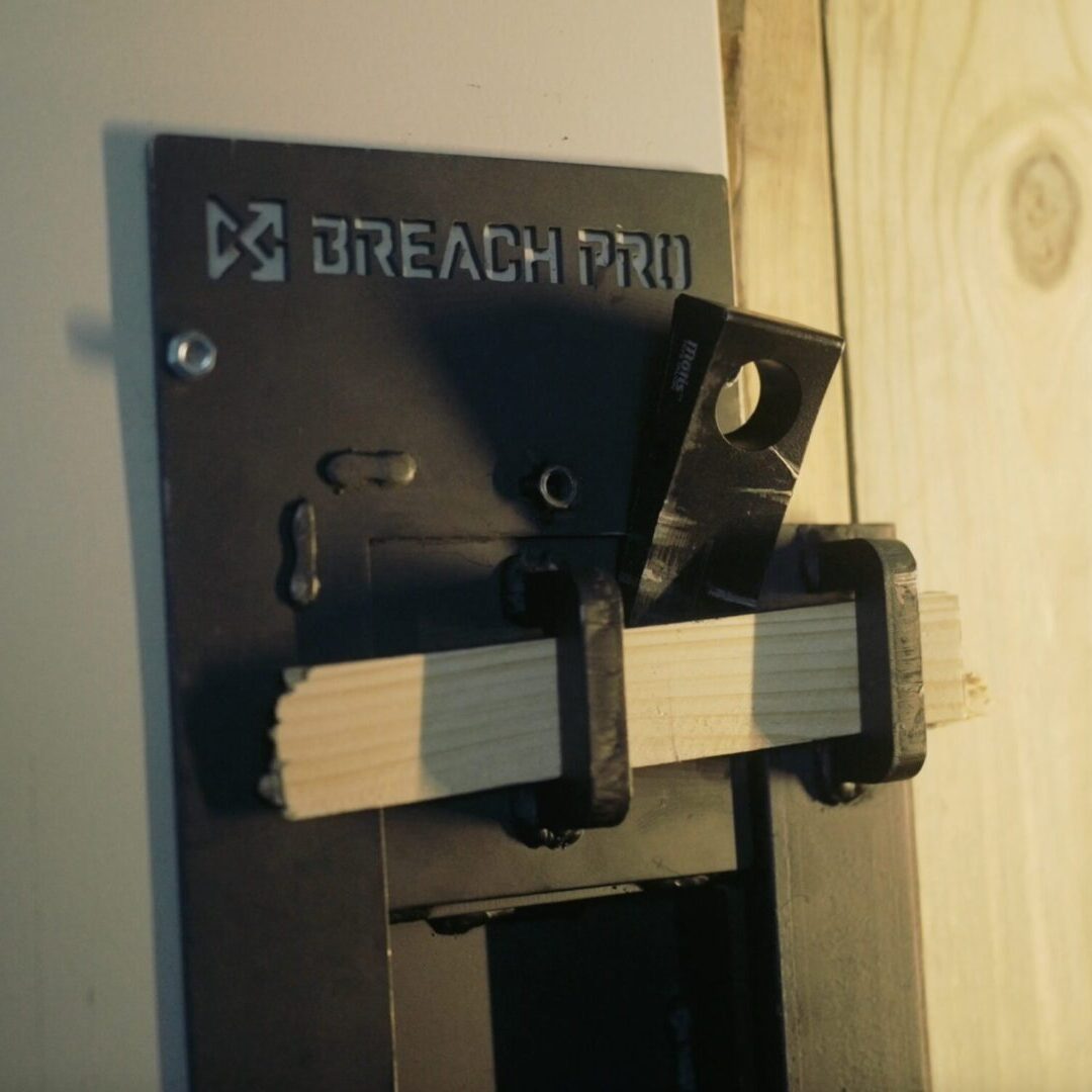 Modular breaching door insert installed in a standard door frame, showing realistic lockset engagement and repeatable training construction for mechanical breaching drills.